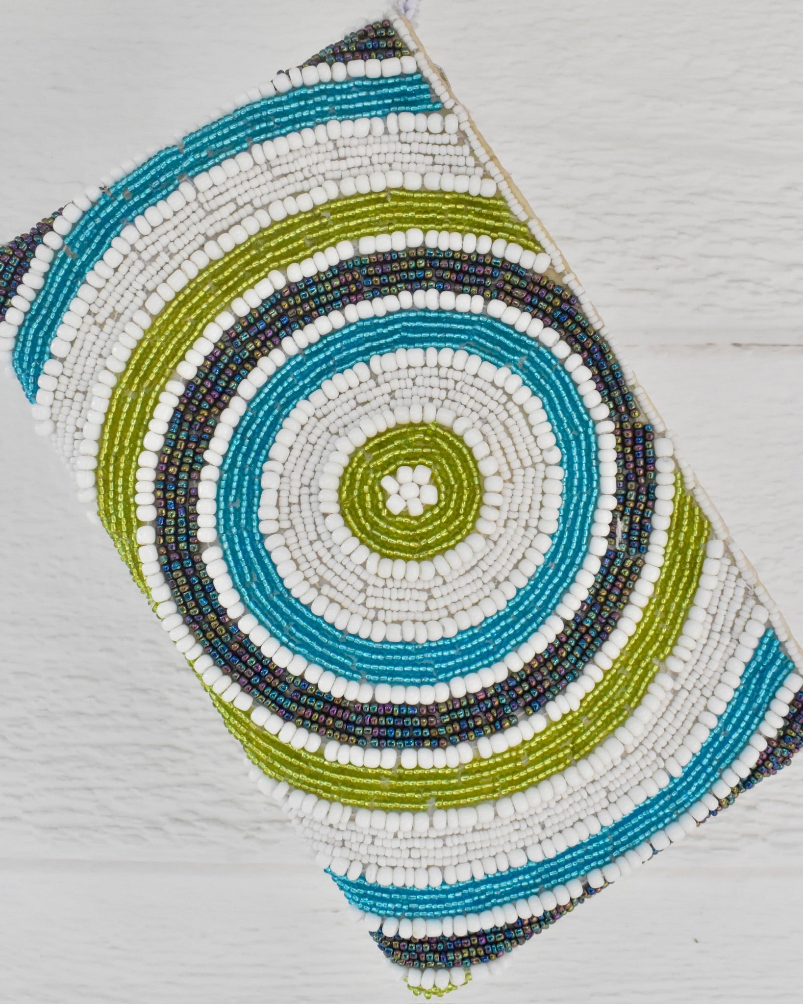Decorative item with concentric circular pattern in blue, green, and white on a light gray background