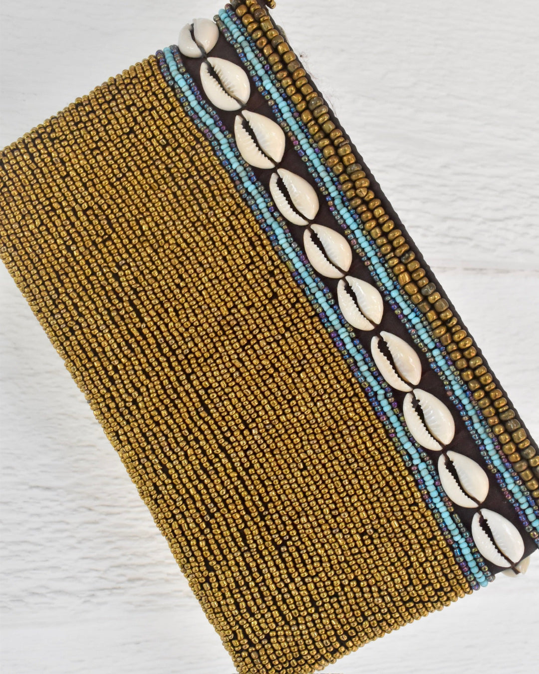 gold beaded clutch and shell pattern on a white background