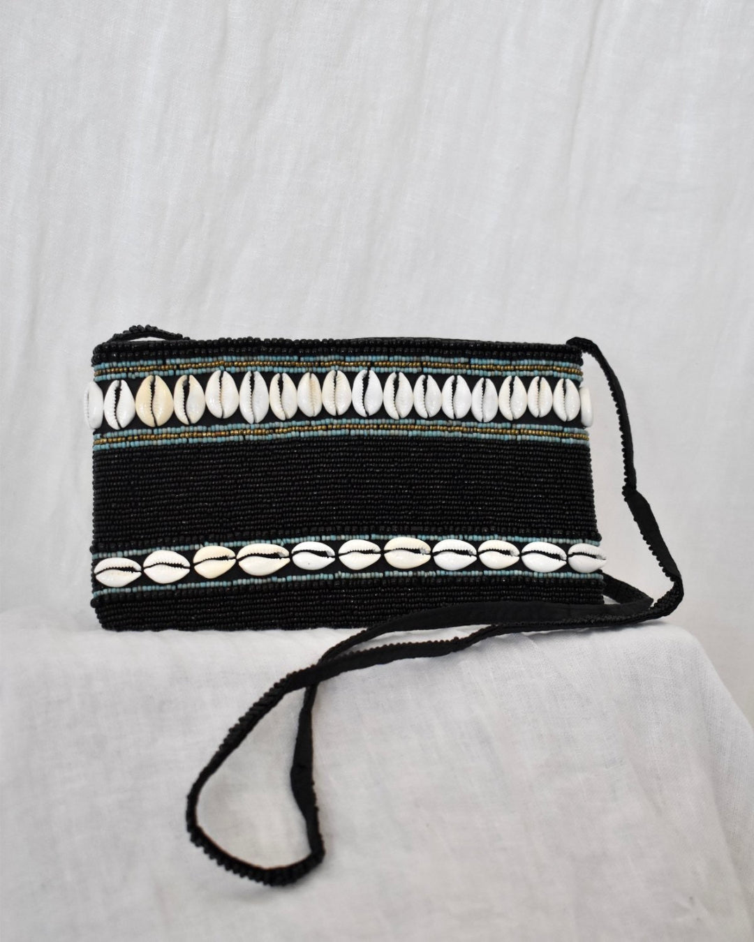 Black clutch bag with shell embellishments on a white background