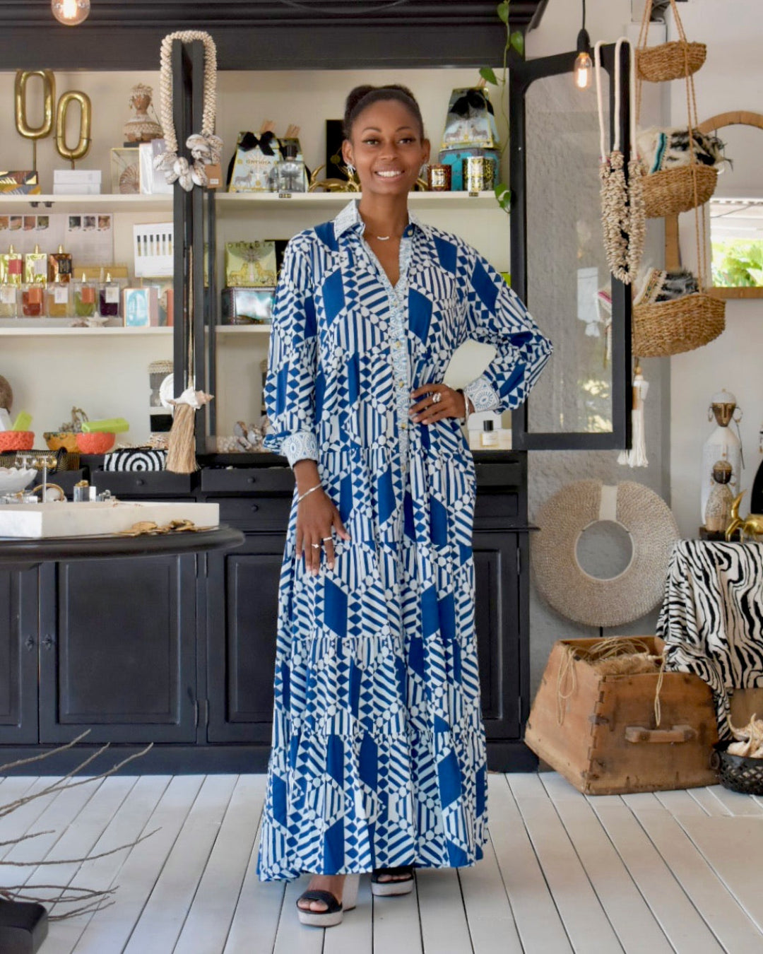 Woman in a blue and white patterned dress standing.