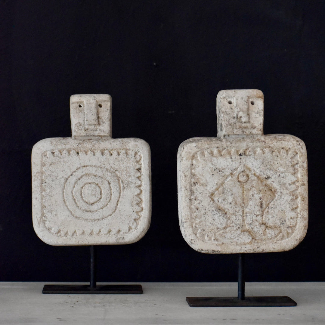 Two decorative bottles with unique designs on stands against a dark background