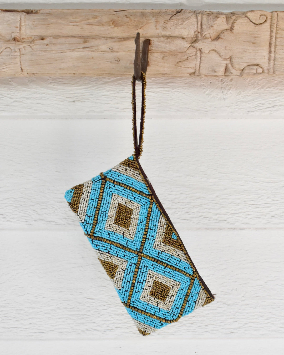 Beaded clutch with geometric pattern hanging on a wooden surface