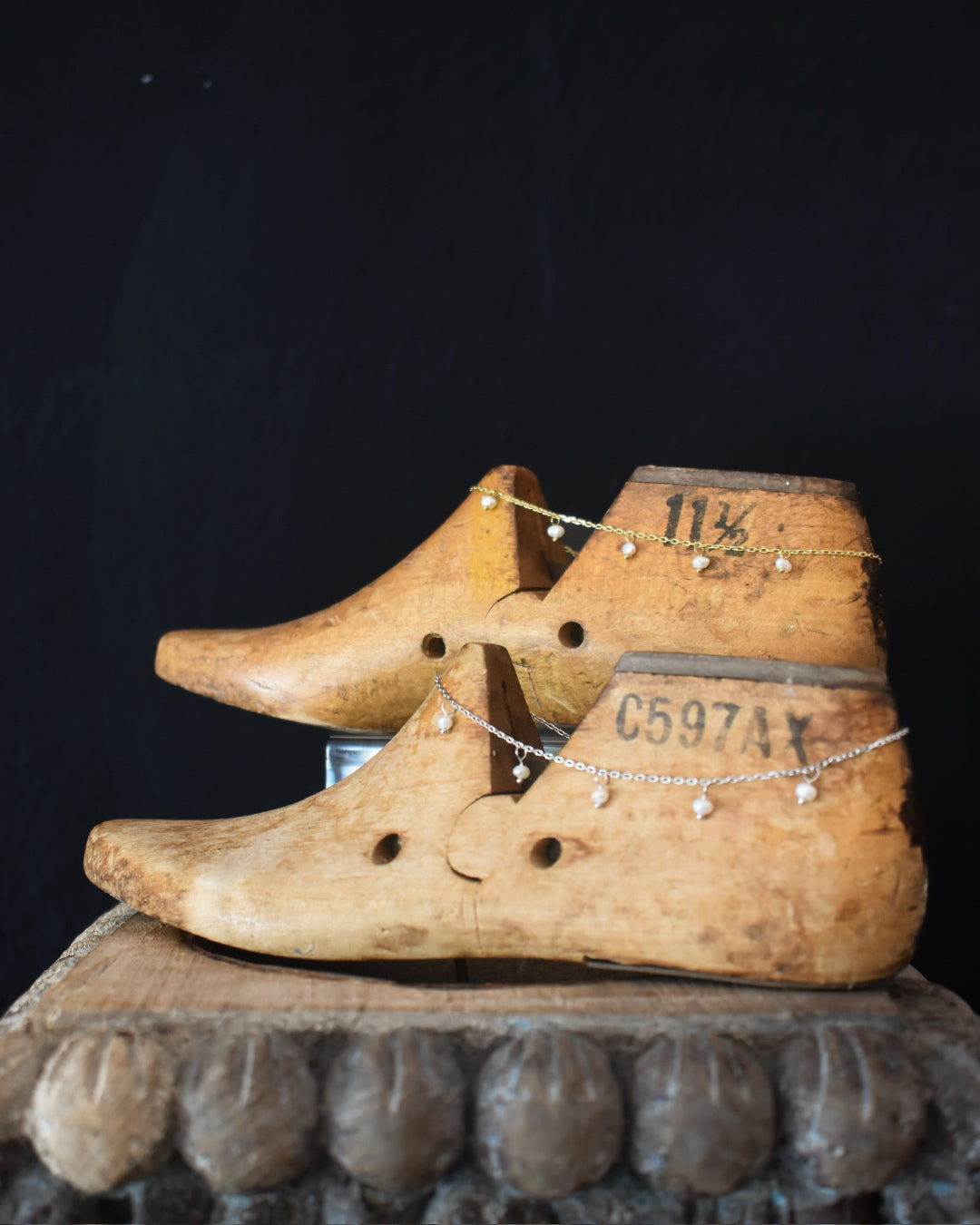 Pair of wooden shoes with visible wear on a dark background