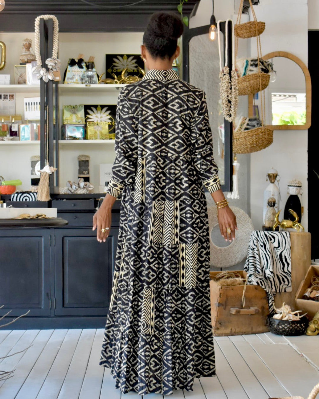 Woman in a black and white patterned dress standing in a stylishly decorated room.