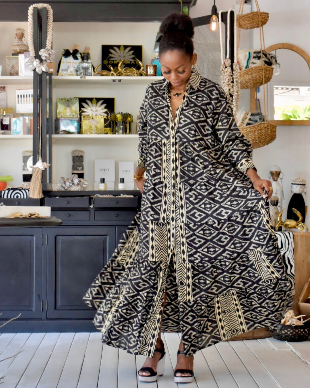 Woman wearing a long, patterned dress in a home setting.