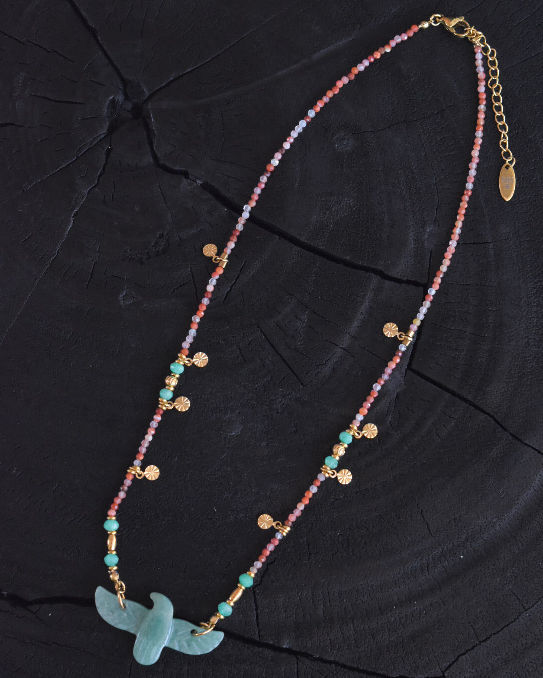 Colorful beaded necklace with a gold chain on a black background