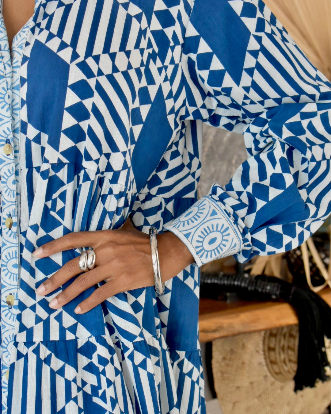 Person wearing a blue and white geometric patterned outfit with a blurred background