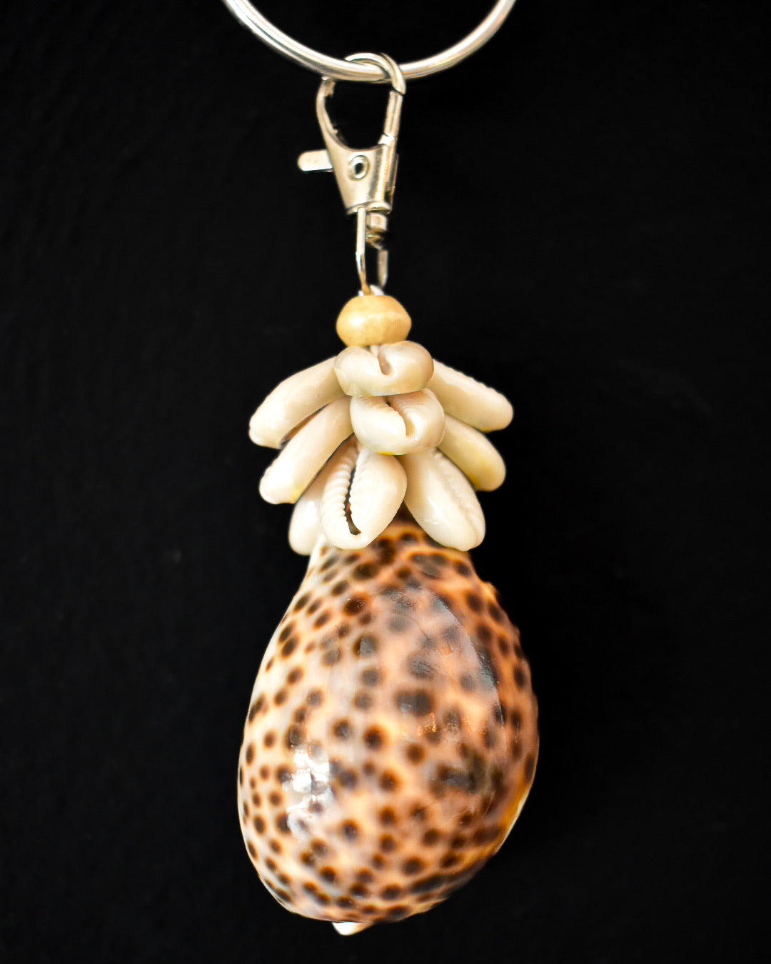 Shell keychain with decorative elements on a black background