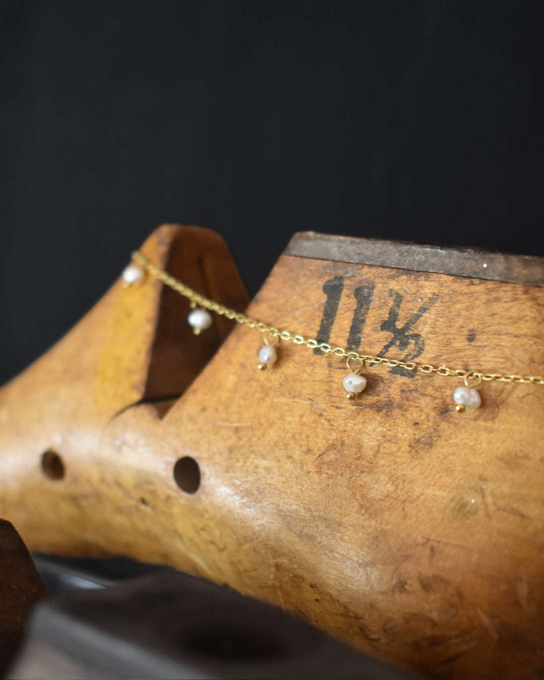 Gold anklet with pearls on a wooden block