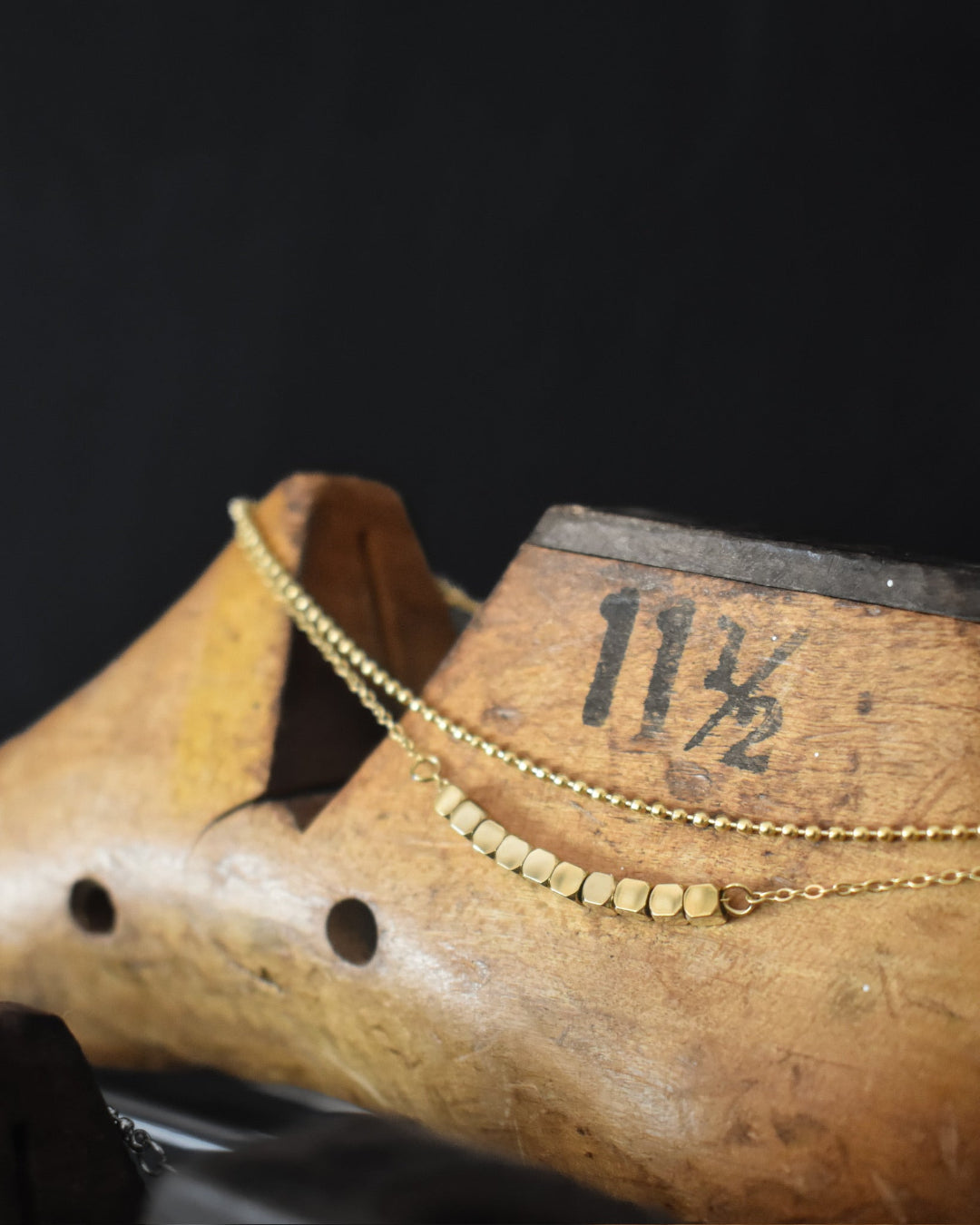Gold bracelet on a wooden shoe with measurement markings