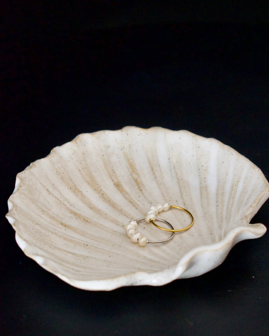 Shell-shaped trinket dish with jewelry on a black background