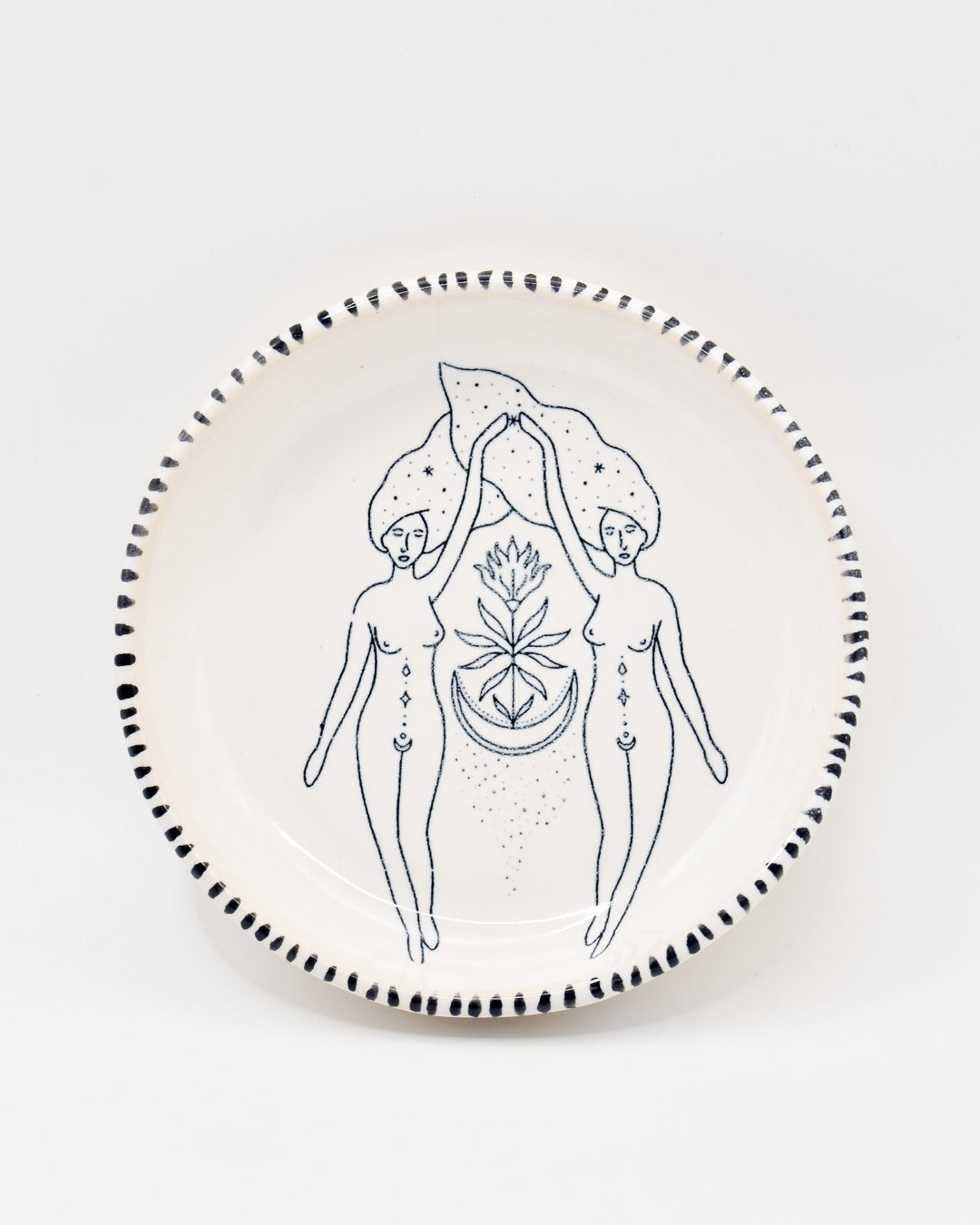 Ceramic plate with black line art of two figures holding a plant design on a white background
