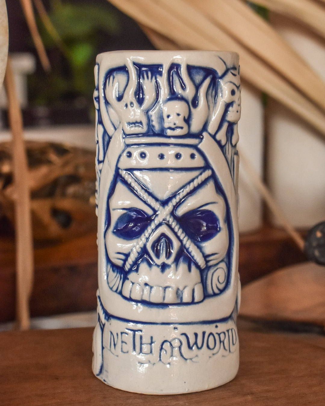 Ceramic mug with blue skull design and text on a wooden surface